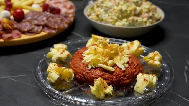 A festive Christmas dinner featuring a gourmet steak tartare centerpiece, served with a side of traditional french salad, artisan cheese, and premium cold cuts for a holiday feast, close-up view