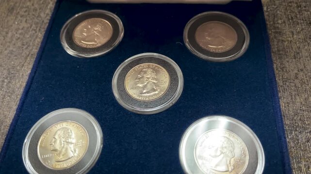 Close up video showing a complete 1999 United States quarter dollar coin set arranged inside a blue presentation box with protective capsules.