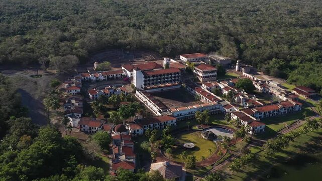 Drone aerial shot of the abandoned ghost hotel beside the Lagoon of Seven Colors in Bacalar, Mexico. Unique ruins surrounded by turquoise water, tropical nature, and iconic travel scenery.