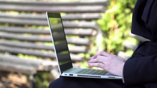 Hands typing on laptop for remote digital nomad work outdoors with copy space