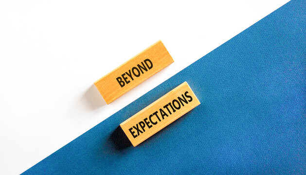 Beyond expectations words symbol. Concept words Beyond expectations on beautiful wooden blocks. Beautiful white and blue background. Business and Beyond expectations words concept. Copy space.