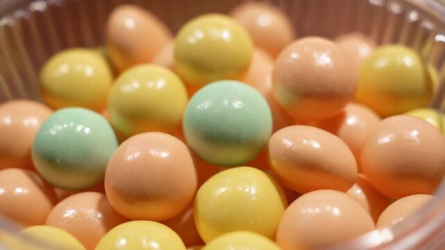 A high-resolution macro of a collection of round, spherical hard candies in a clear bin. Ai