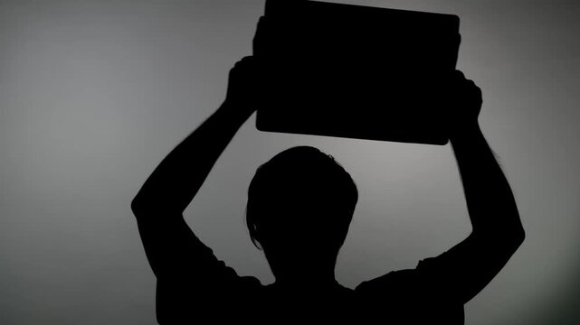 An anonymous silhouette of a person holds a banner over his head and waves it in protest