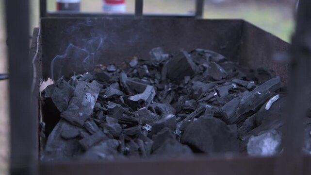 A close-up of charcoal in a grill being doused with lighter fluid
