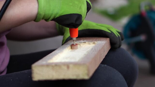 Working with an engraver. A woman cuts and processes wood; a woman creates handmade wood crafts using an engraver. Handcrafted woodwork in progress.
