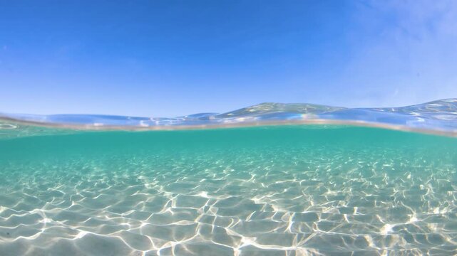 Slow motion split underwater view at La Pelosa beach showing clear turquoise sea above and below the water surface