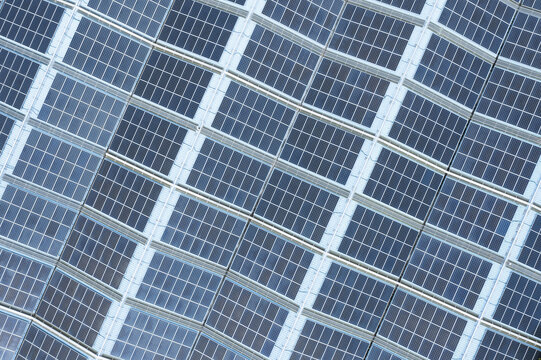 Aerial view of solar panels on the factory roof arranged in a geometric grid pattern with blue photovoltaic cells in Taiwan.