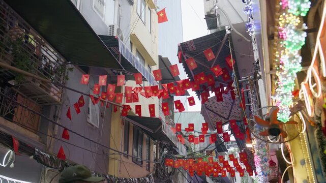 Vietnamese communist flags decorating narrow alley in Hanoi Old Quarter, Vietnam, reflecting country's patriotism and cultural identity