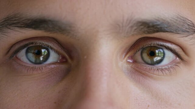 Starting center gaze, man is shifting eyes right, returning near window, reacting to camera in eyes