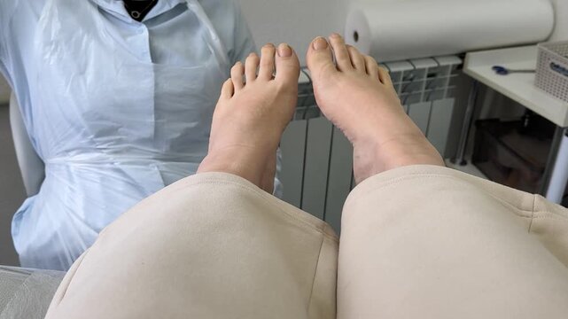 Close-up of a woman seated in a pedicure chair during a salon treatment. The technician adjusts the chair position to raise and lower the leg support for optimal comfort and proper procedure setup.
