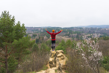 A tourist climbs a high cliff in a nature park and admires the beautiful spring landscape from above. The Kislovodsk Nature Park in the Caucasus is the largest urban park in Europe