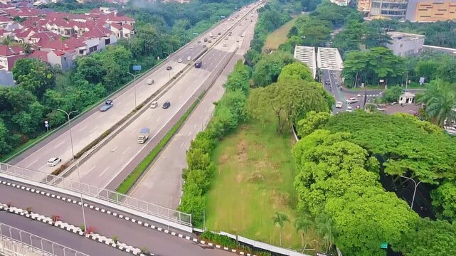Aerial Drone View of Highway Traffic Passing Urban Residential Area with Green Landscape