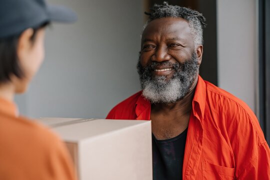 Older bearded man smiling while receiving package at door