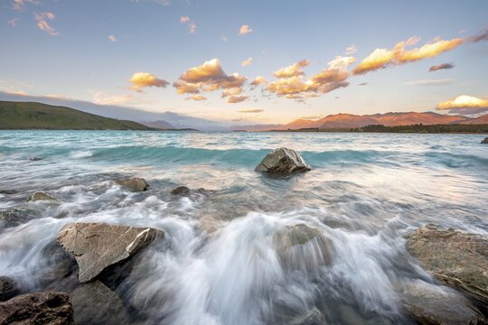 Stones on shore, lake with sunset swell, long time exposure, Lake Tekapo, Canterbury, South Island, New Zealand