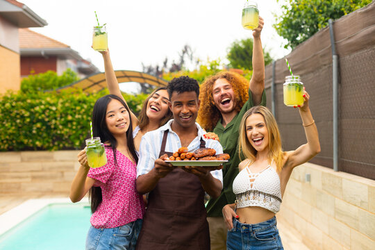Friends raising glasses with lemonade, celebrating barbecue party by the pool