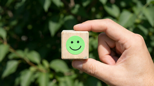 hand holding wooden block with green smiley face
