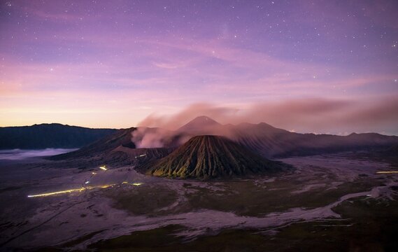 Volcanic landscape at sunrise with starry sky, smoking volcano Gunung Bromo, with Mt. Batok, Mt. Kursi, Mt. Gunung Semeru, National Park Bromo-Tengger-Semeru, Java, Indonesia