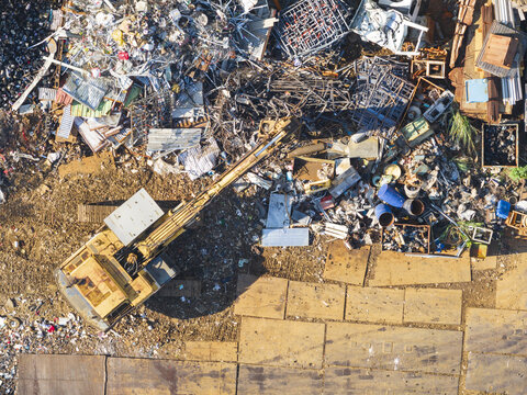 Aerial view of Resource recovery plant with an excavator moving scrap metal and debris among piles of industrial waste Taiwan.