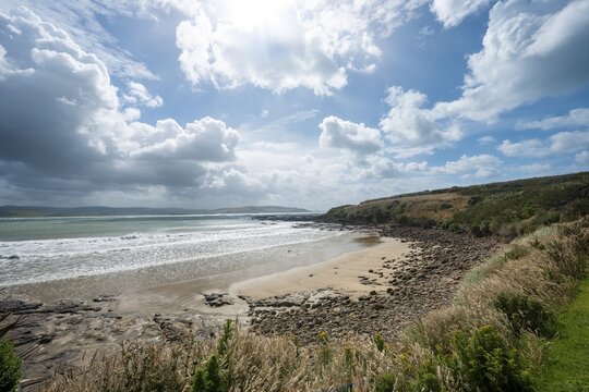 View of sandy beach and sea at Curio Bay, cloudy sky, Curio Bay, Southland, South Island, New Zealand