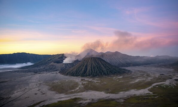 Volcanic landscape at sunrise, smoking volcano Gunung Bromo, with Mt. Batok, Mt. Kursi, Mt. Gunung Semeru, Bromo-Tengger-Semeru National Park, Java, Indonesia