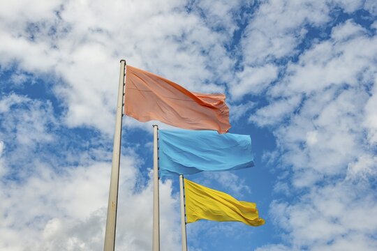 Red, blue and yellow flag in front of cloudy sky, Berlin, Germany