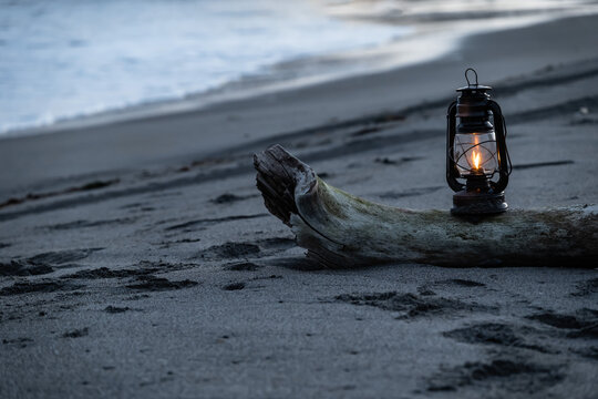 夕暮れの砂浜に置かれたアンティークなハリケーンランタン
