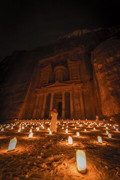 Man with flute, candles in front of the Pharaoh's treasure house, carved in rock, at night, facade of the treasure house Al-Khazneh, Khazne Faraun, mausoleum in the Nabataean city Petra, near Wadi Musa, Jordan