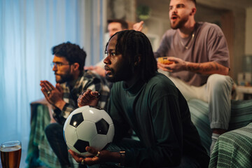 Diverse men watching live soccer game at home, feeling excitement and anticipation during sport event © Zamrznuti tonovi