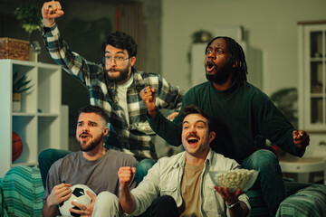 Diverse friends gathering, watching a football game at home, expressing excitement and cheering for a victory © Zamrznuti tonovi