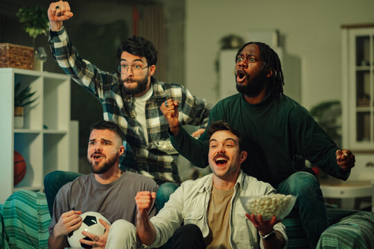 Diverse friends gathering, watching a football game at home, expressing excitement and cheering for a victory