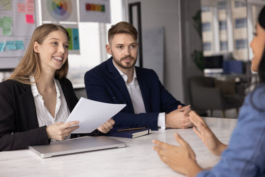 Smiling Indian woman vacancy candidate passing job interview, sits at table with two recruiters, speaks about education, professional skills and competence. Headhunt, company staffing, human resources