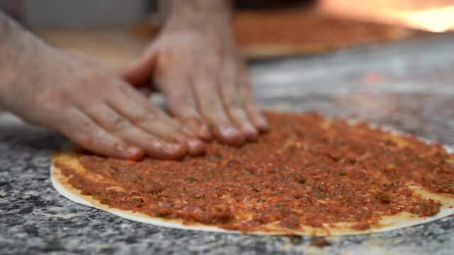 Chef making Turkish pizza lahmacun in bakery kitchen