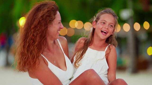 Mother and her cute little daughter spending time together laughing on the beach of a tropical island on vacation enjoying each other. Concept of motherhood childhood and spending time together