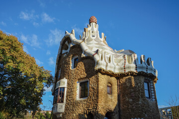 Park Guell,Barcelona,Spain,Unusual stone building with ornate white roof and turrets under a clear blue sky © SHUNJI ZHOU