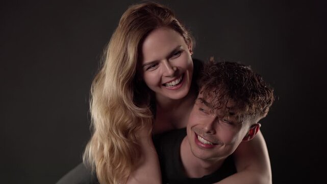 Young athletic woman laughing on her boyfriend's back while enjoying a piggyback ride