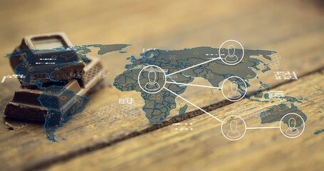 Fototapeta premium Projecting thin world map overlay across wood table, with dark chocolate stack and user nodes