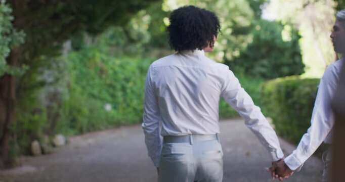 Diverse group walking path couple with senior holding hands in white shirts with friends joining