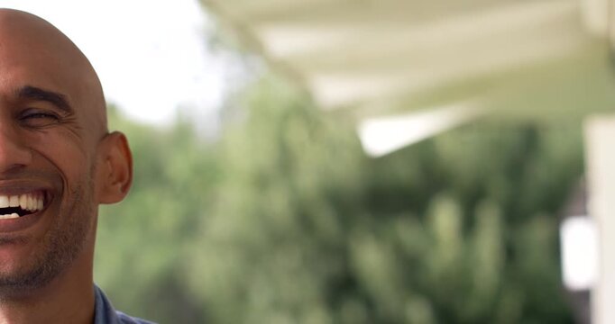 Adult African American man blue-shirt reacting to joke smiling laughing on porch awning, copy space