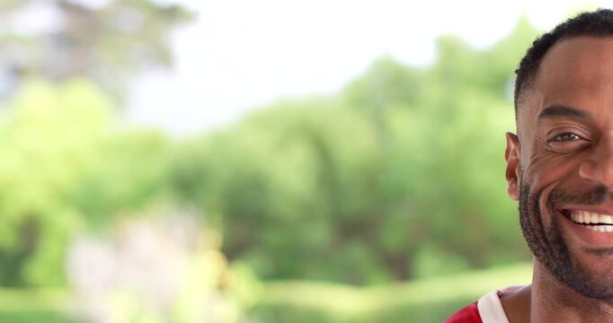 African American man smiling, tilting head, reacting to cue in garden, red jersey, copy space