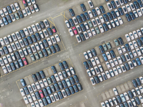 Aerial view of a car dealer parking lot with rows of new vehicles on asphalt in Taiwan.