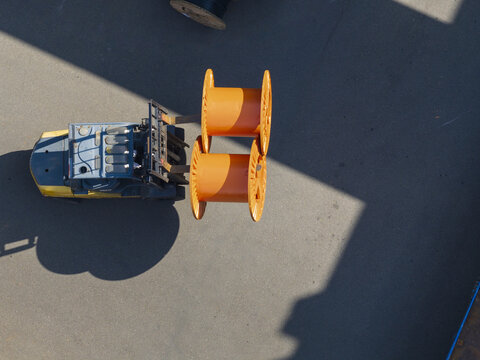 Aerial view of a cable factory with a forklift carrying two large orange cable reels on an asphalt yard Taiwan.
