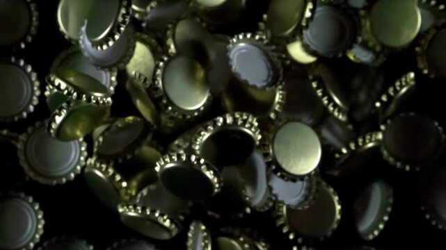 Many Beer Bottle Caps. Golden beer bottle caps floating in the air on a black background. Slow Motion