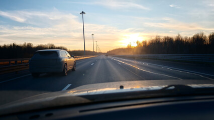 Obraz premium Car driving on a highway during sunset on a clear day