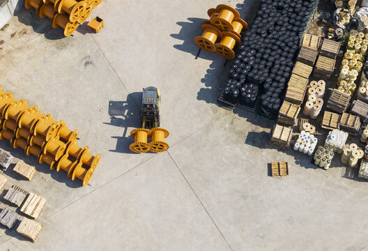 Aerial view of a cable factory with a forklift operator moving large yellow cable spools in an industrial yard in Taiwan.
