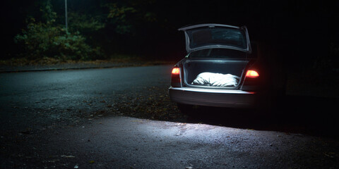 Car trunk open with person inside at night