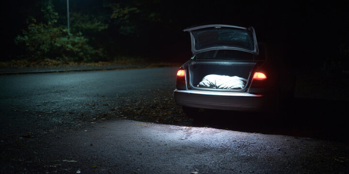 Car trunk open with person inside at night