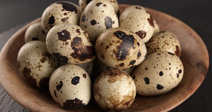 Quail eggs in a wooden bowl, close-up footage on a rotating table.