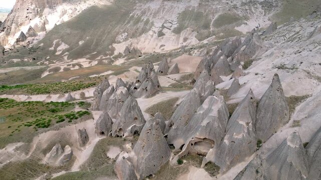 Drone Shot of Cave Windows in Selime Fairy Chimneys. A high-resolution aerial perspective focusing on the unique fairy chimney rock formations and hand-carved cave windows at the Selime archaeological