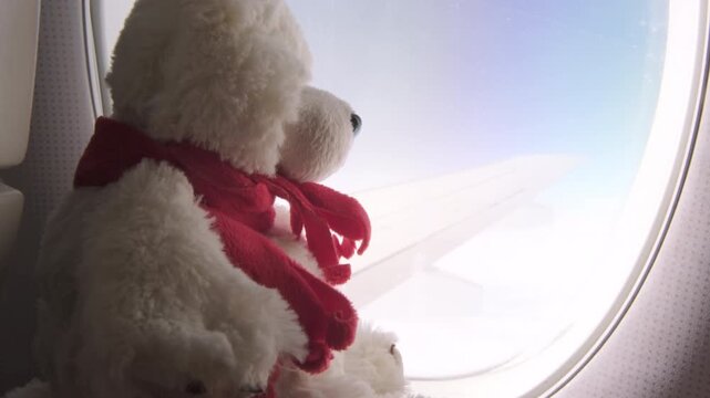 Soft toy bear against background of airplane window during flight
