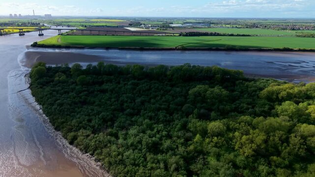 High angle drone view of the green Howden Dyke Island sitting in the middle of the brown tidal estuary of the River Ouse near Goole Yorkshire UK